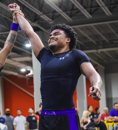 Binyamin Downs in a black rash guard having his hand raised by the referee after a win
