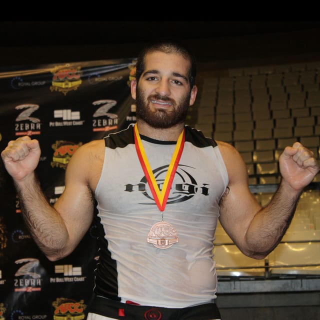 David Avellan with both arms raised, wearing a bronze medal, at the 2009 ADCC Submission Wrestling World Championships