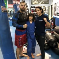 Sean Hotusing con su esposa y su hija, que lleva un kimono azul de jiu-jitsu, en Freestyle Fighting Academy