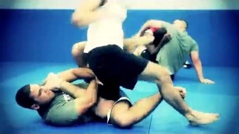 Two students grappling on the blue mats at Freestyle Fighting Academy while others train in the background