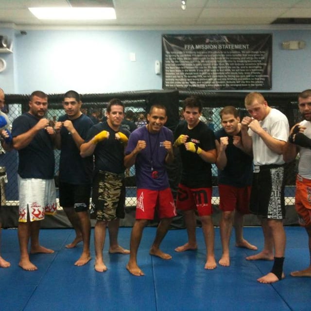Una fila de estudiantes adultos en guardia, con vendas y guantes, durante una clase de Muay Thai en Freestyle Fighting Academy en Miami