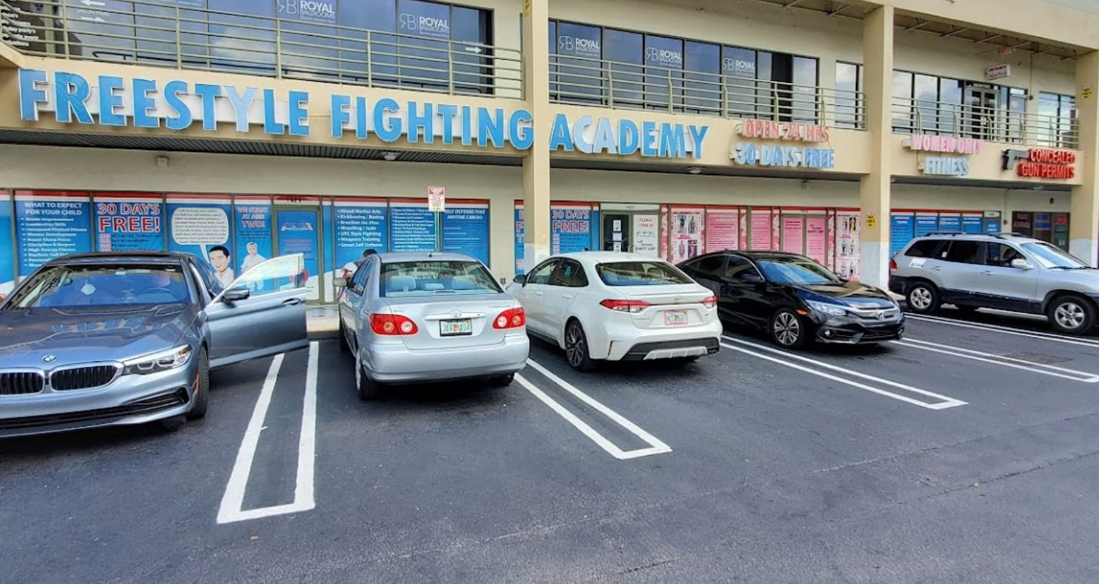 The Freestyle Fighting Academy storefront on SW 107th Ave in Miami: a wide blue sign reading FREESTYLE FIGHTING ACADEMY above the entrance, with marked parking spaces directly in front